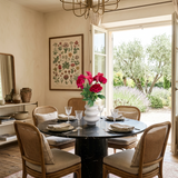 NO. 50 by Nicolíe de Luxe: deep pink peonies and pink calla lilies in a stacked white sculptural vase, styled on a round marble dining table in a villa dining room opening to an olive garden