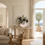 NO. 75 by Nicolíe de Luxe: white holly berry clusters and deep green foliage in a round speckled stone vase, styled on a travertine console in a bright Marbella villa living room