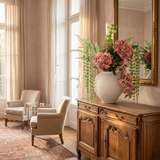 NO. 23 by Nicolíe de Luxe: coral hydrangeas, peach orchids and cascading string-of-pearls in a cream stoneware vase, styled on an antique French sideboard in a blush-walled salon