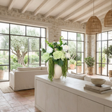 NO. 24 by Nicolíe de Luxe: green hydrangeas, white double peonies and cascading green amaranthus in a cream stoneware vase, styled on a plaster sideboard in a beamed Marbella villa great room