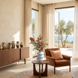 NO. 38 by Nicolíe de Luxe: peach orchid spray, burnt-orange anthuriums and fern in a stacked white sculptural vase, styled on a walnut side table in a sea-view Marbella villa living room