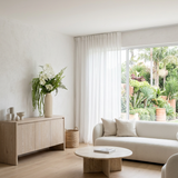 NO. 35 by Nicolíe de Luxe: white lilac and viburnum, fern and cascading green amaranthus in a slim cream bottle vase, styled on an oak sideboard in an airy villa living room