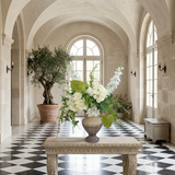 NO. 63 by Nicolíe de Luxe: white hydrangeas, white delphinium, green anthuriums and airy greenery in a stone urn vase, styled on a carved stone console in a vaulted villa entrance gallery