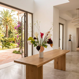 NO. 66 by Nicolíe de Luxe: white and pink calla lilies, burgundy and blush anthuriums, a white peony and looping stems in a white cylindrical vase, styled on an oak console table in a Marbella villa entrance hall