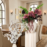 Villa Package NO. 2 by Nicolíe de Luxe: burgundy and blush hydrangeas with trailing amaranthus on a fluted cream pedestal beside white cherry blossom branches, styled in a Marbella villa dining room